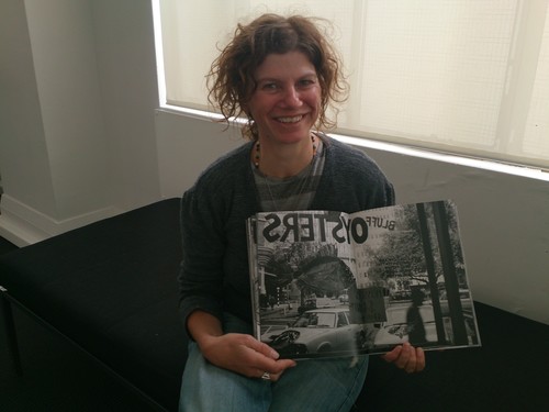 Gina with the photograph of a sign she painted for her father's shop, included in the exhibition's accompanying publication.
