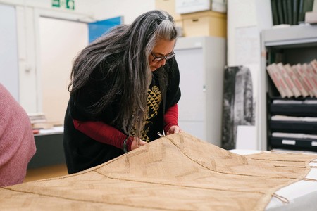 Donna Campbell inspecting Te Rā at the British Museum. © The Whakaarahia anō te rā kaihau Te Rā Project. Photo: Adam Rowley