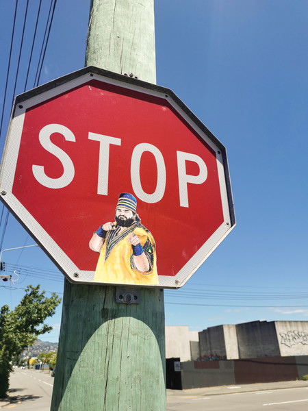 A stop sign is altered with the presence of a pasteup of a 1980s professional wrestler.