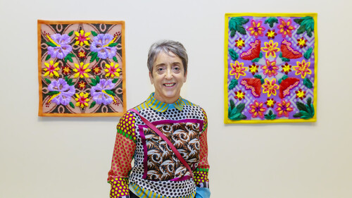 Julie Stewart in front of works by Serene Hodgman from the exhibition Made in the Pacific: A Collection of Tāoga, 2026