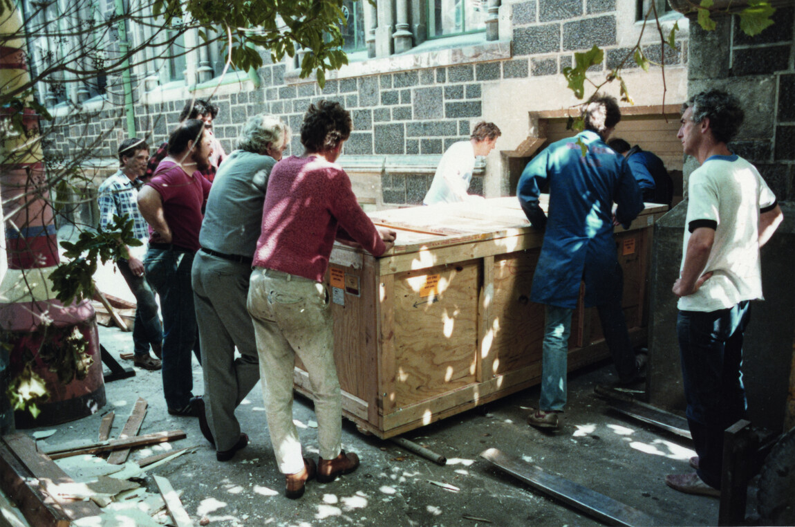 A team of helpers shifting the new lithograph press into the basement of the Gingko Print Workshop, Christchurch Arts Centre, c. 1984. Gingko Print Workshop and Gallery Archives, Robert and Barbara Stewart Library and Archives, Christchurch Art Gallery Te Puna o Waiwhetū